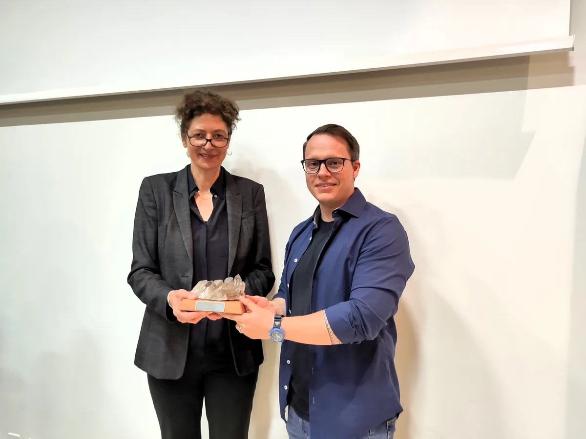 Philipp Zopp überreicht seiner Nachfolgerin Helen Bisang einen Bergkristall aus den Urner Bergen. Es ist ein Geschenk ans Parlament. Man sieht einen Mann, der einer Frau einen Bergkristall überreicht.